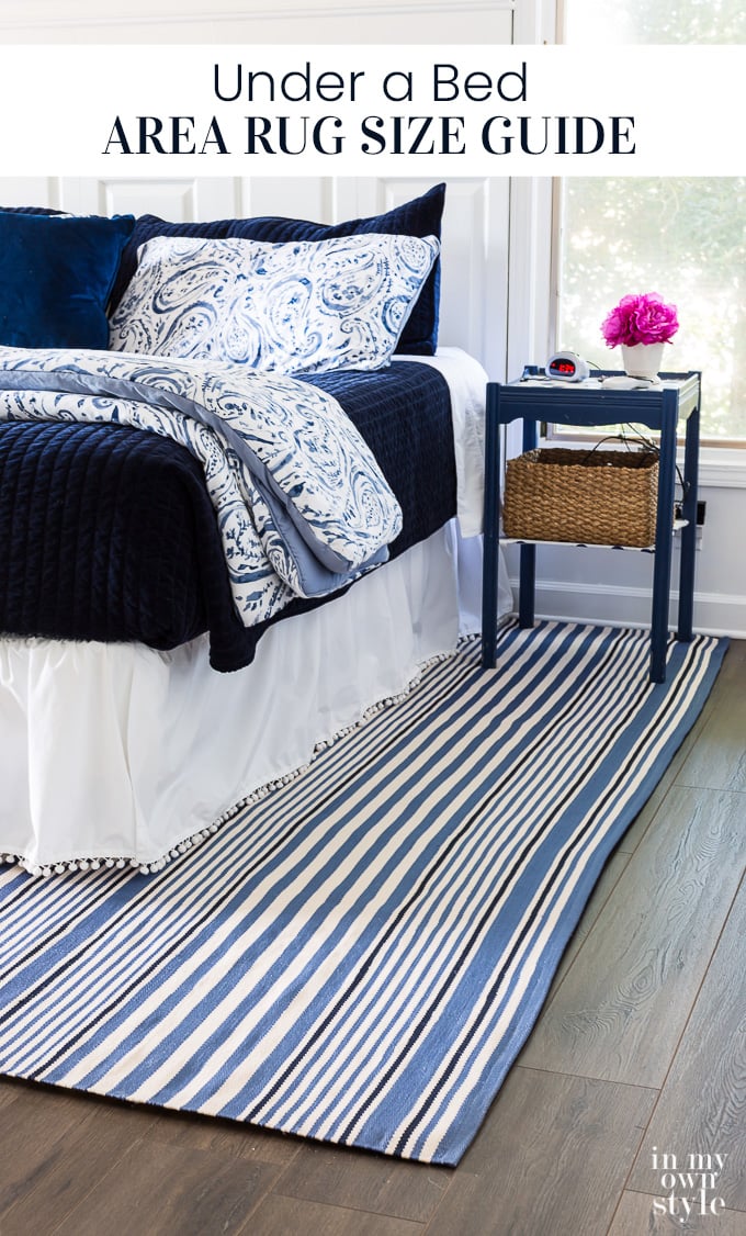 Blue and white decorated bedroom with blue and white striped area rug under the bed.