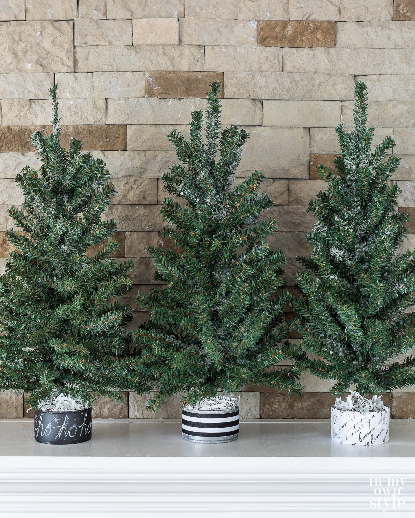 3 mini Christmas trees with black and white bases made using tuna cans