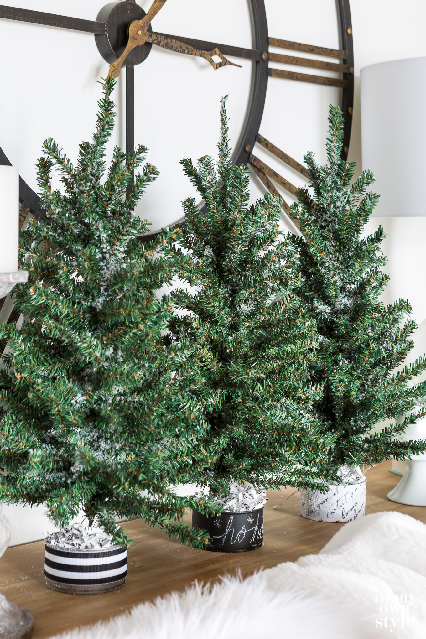A trio of mini faux Christmas trees lined up along a sofa table.
