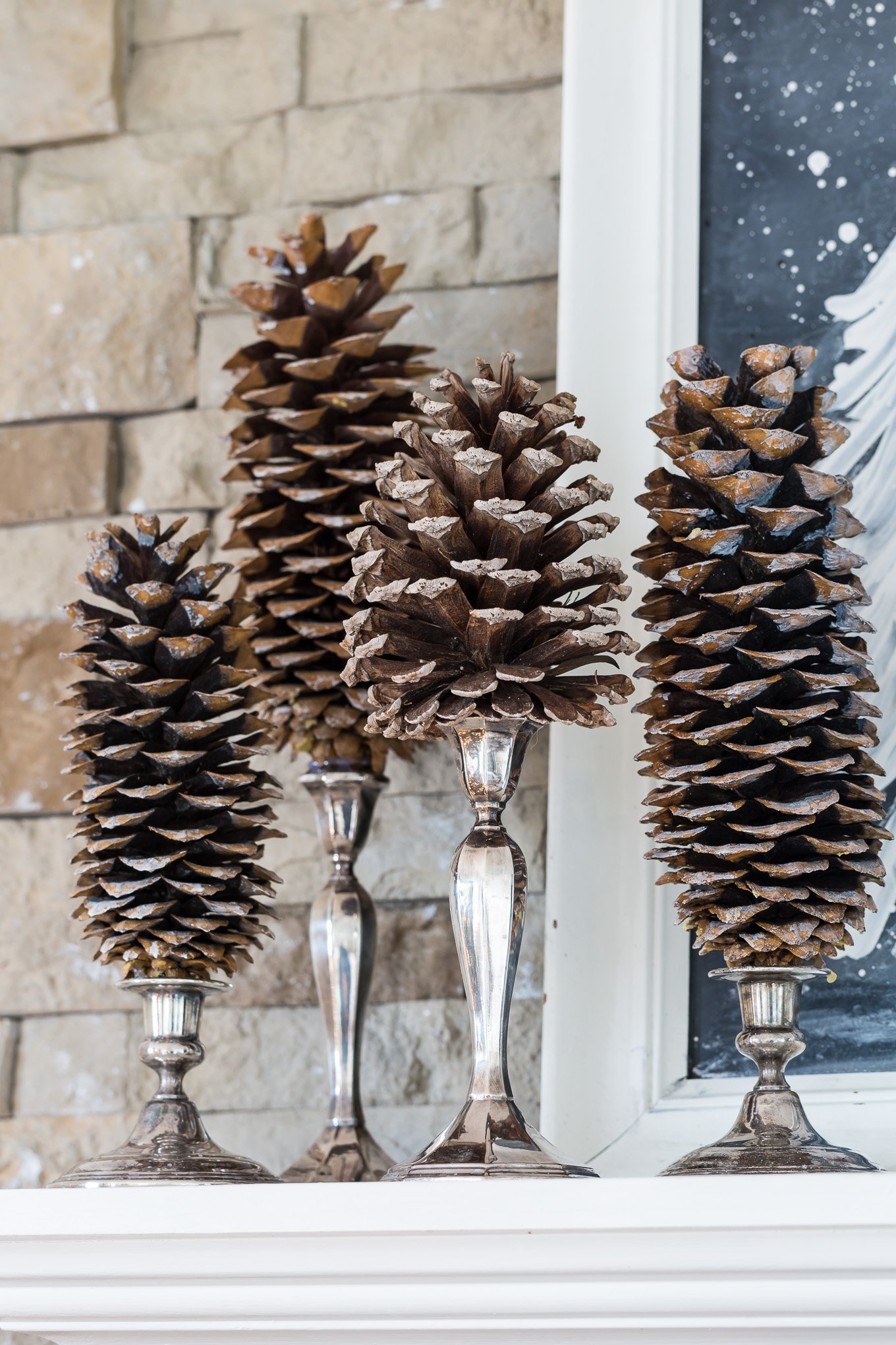 pinecones mounted on silver candlesticks on a mantel decorated for Christmas