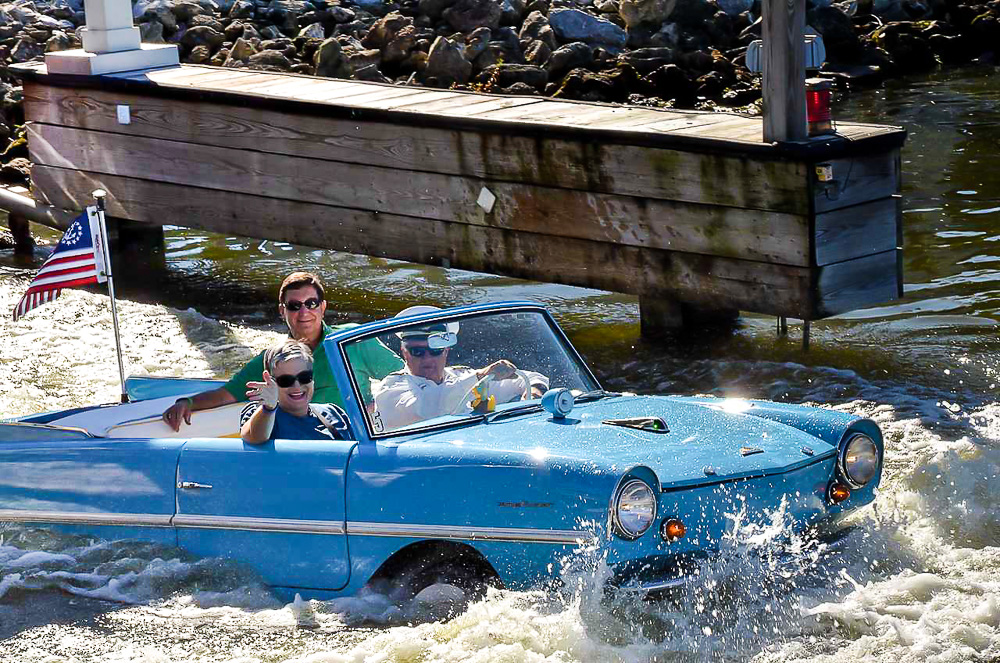 A turquoise vintage Amphicar going into the water from land at Disney Springs in Orlando.