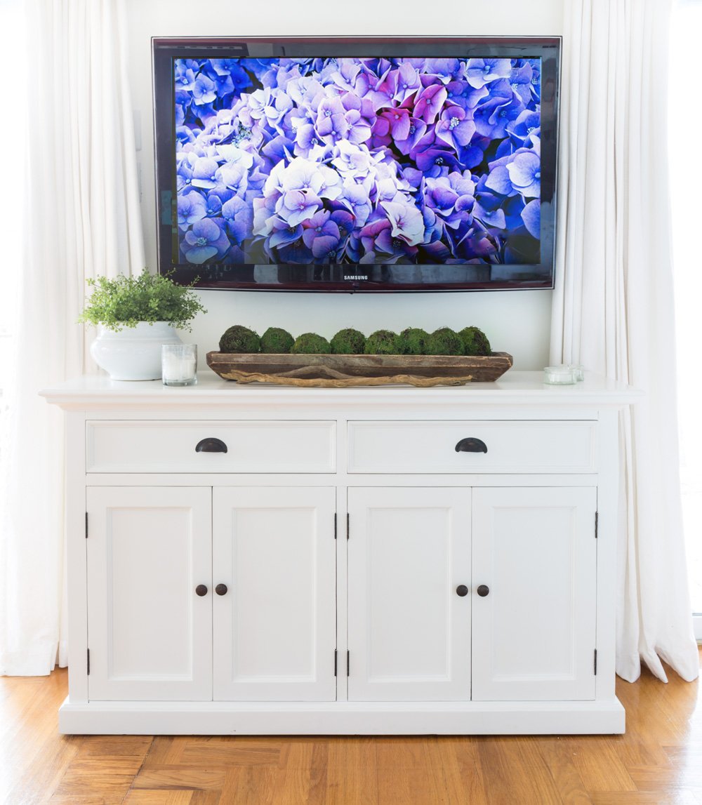White farmhouse furniture below a wall mounted TV