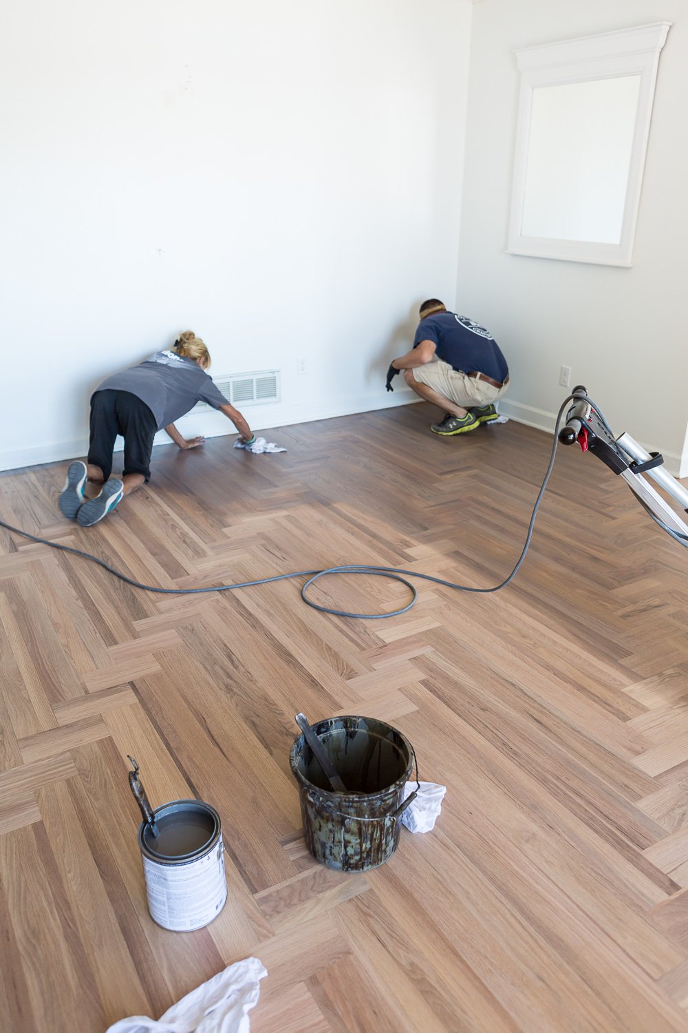 Bona floor refinishing professional staining a hardwood floor along the outer edges of the room using DriFast stain in grey.