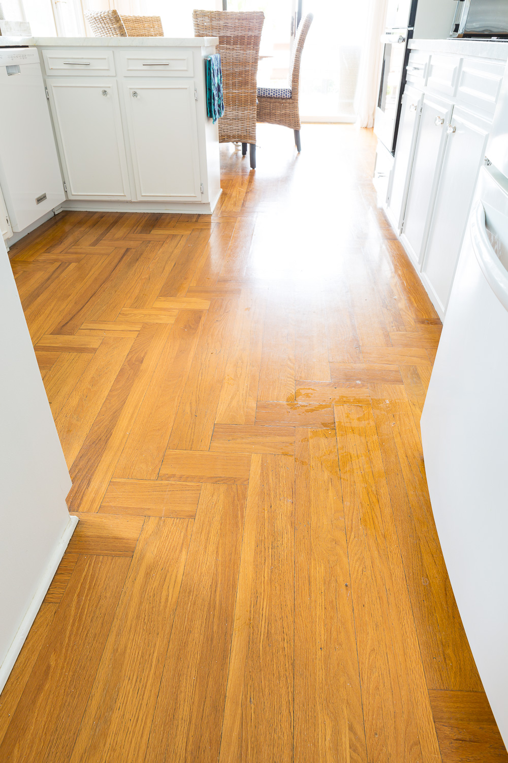 Kitchen with herringbone hardwood floor that has turned orange with age.
