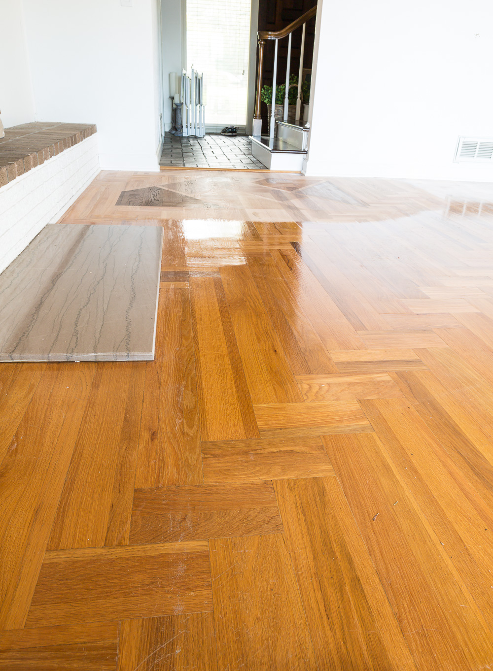 Orange toned wood floor with oil-based polyurethane before getting refinished with the Bona Hardwood Floor Refinishing System