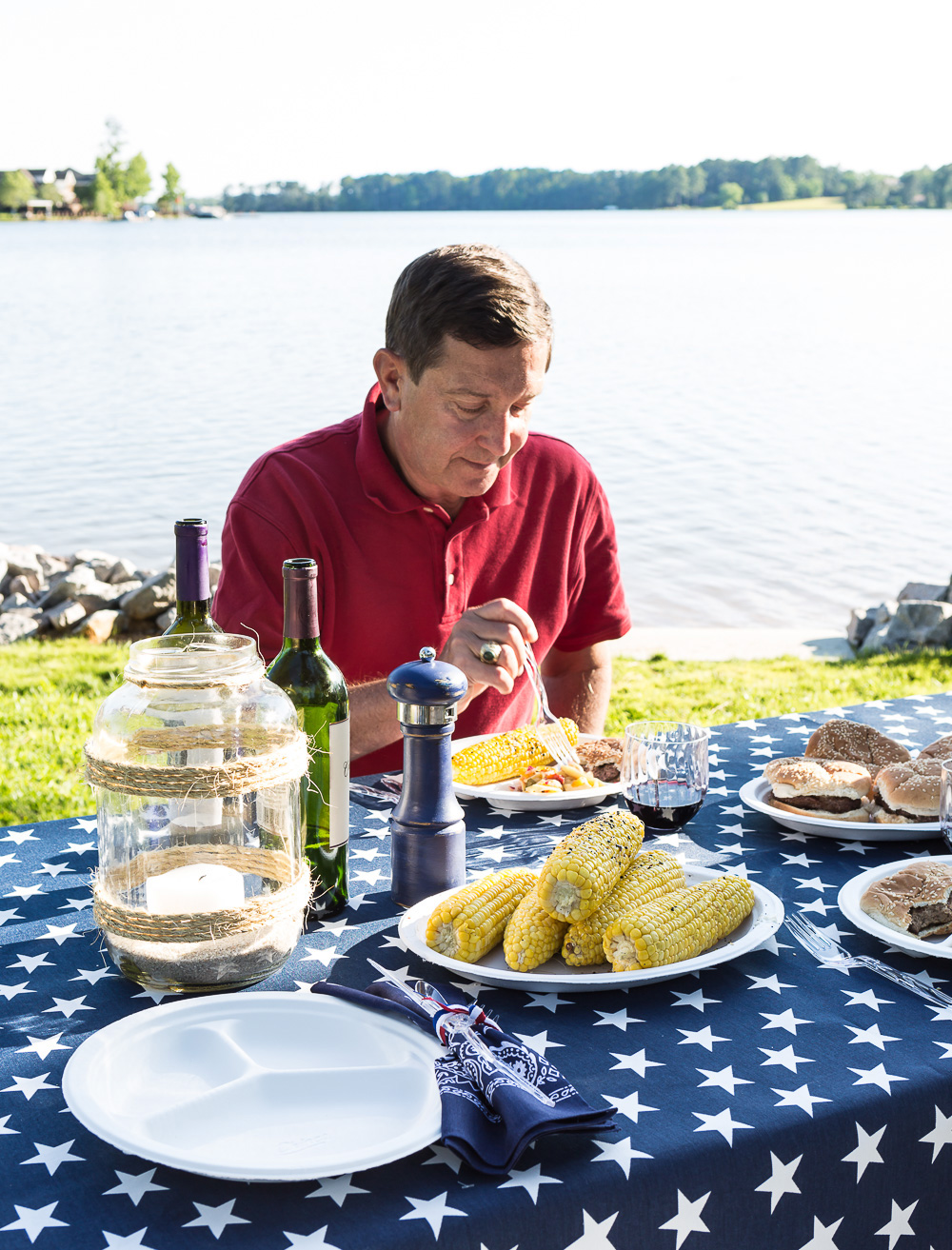 Fourth of July party guest eating at a picnic table along a lake