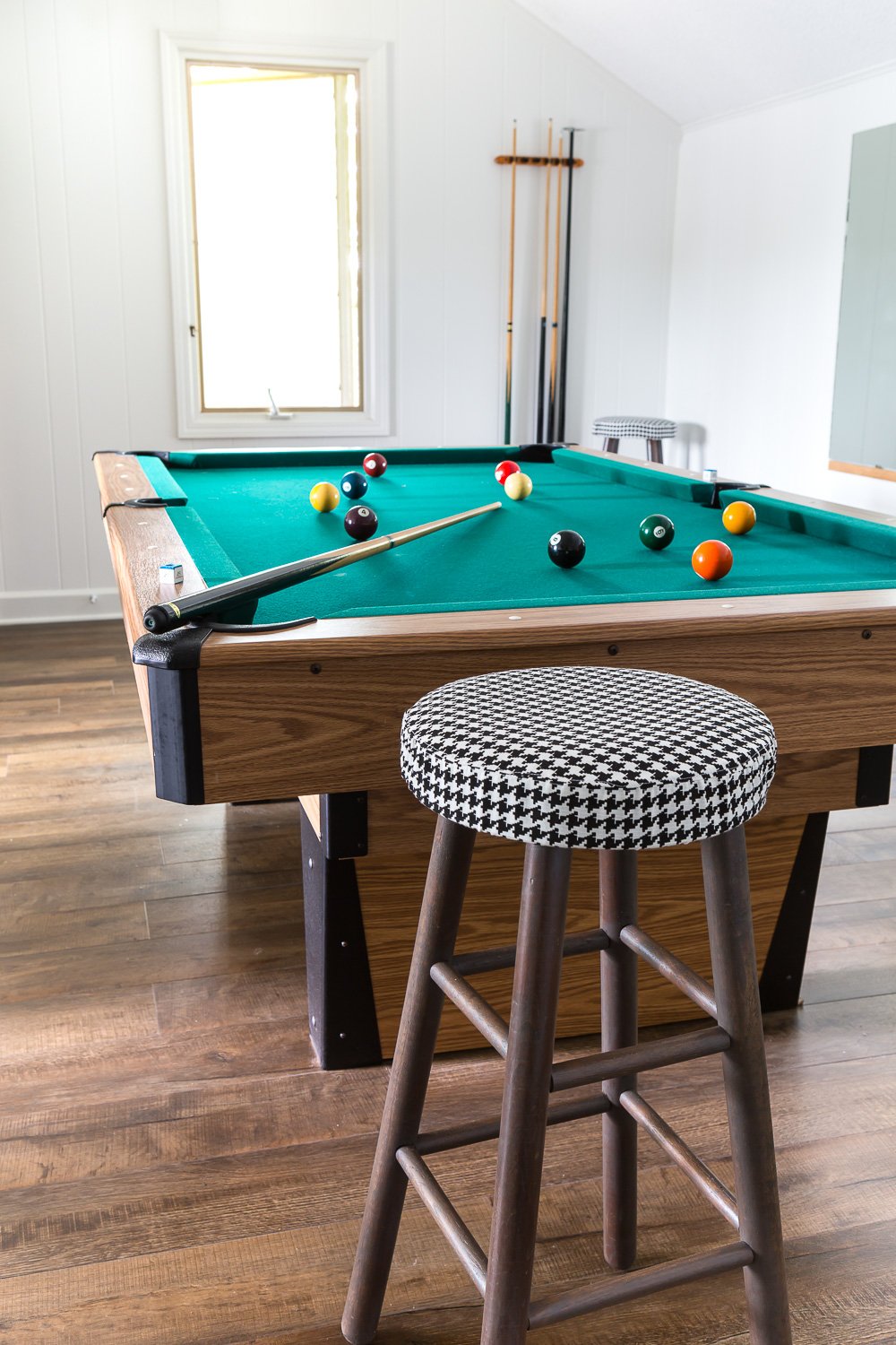 Wood stool painted with new fabric cover in front of a pool table