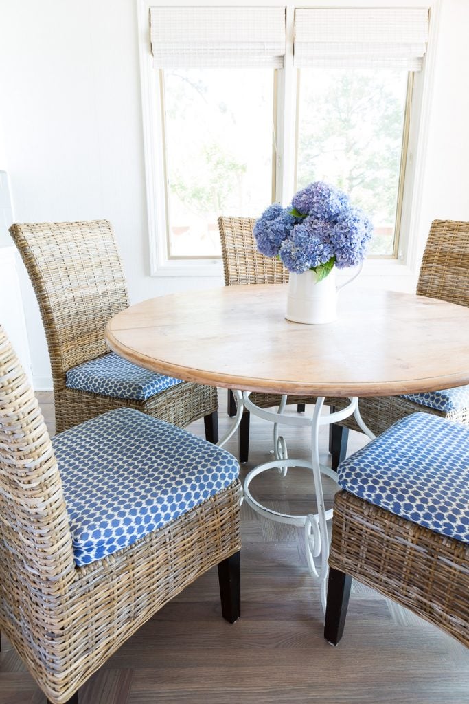 Round wood kitchen table and driftwood colored woven chairs in kitchen.