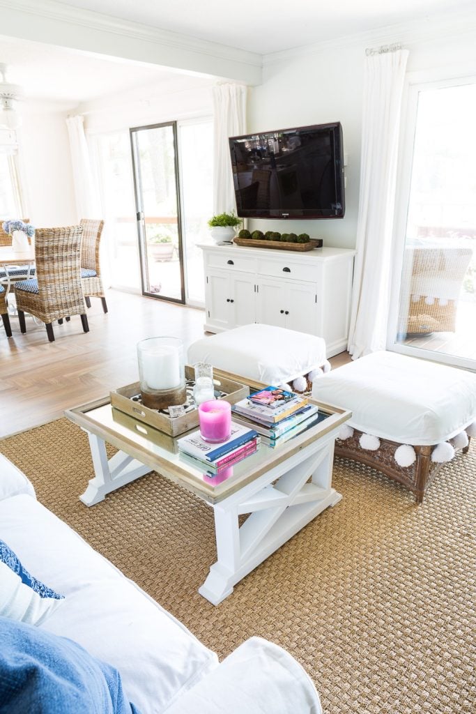 Living room Furniture arranging using ottomans and a seagrass area rug in living room defines the seating space into a conversational grouping.