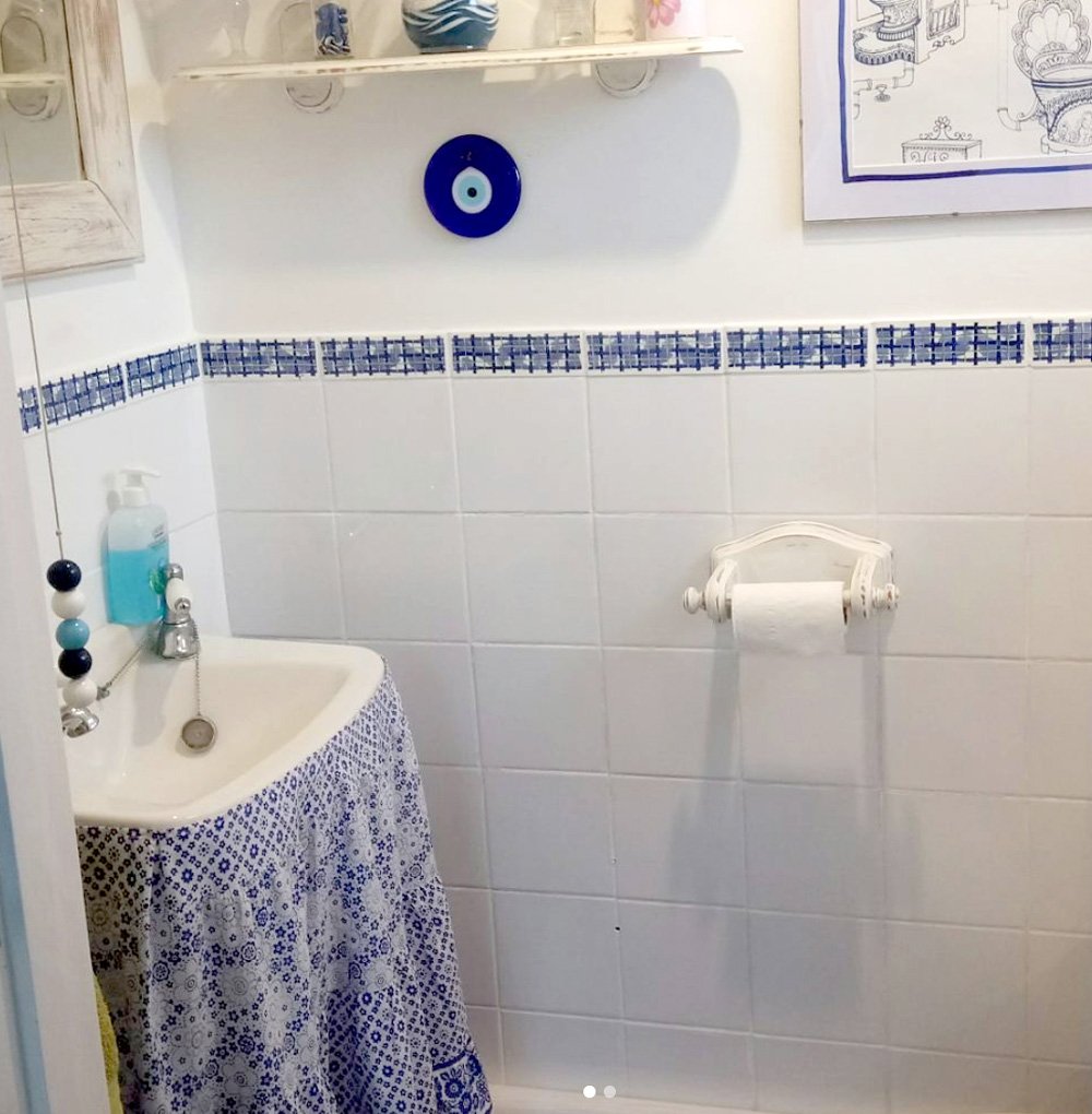 blue and white bathroom with fabric sink skirt.