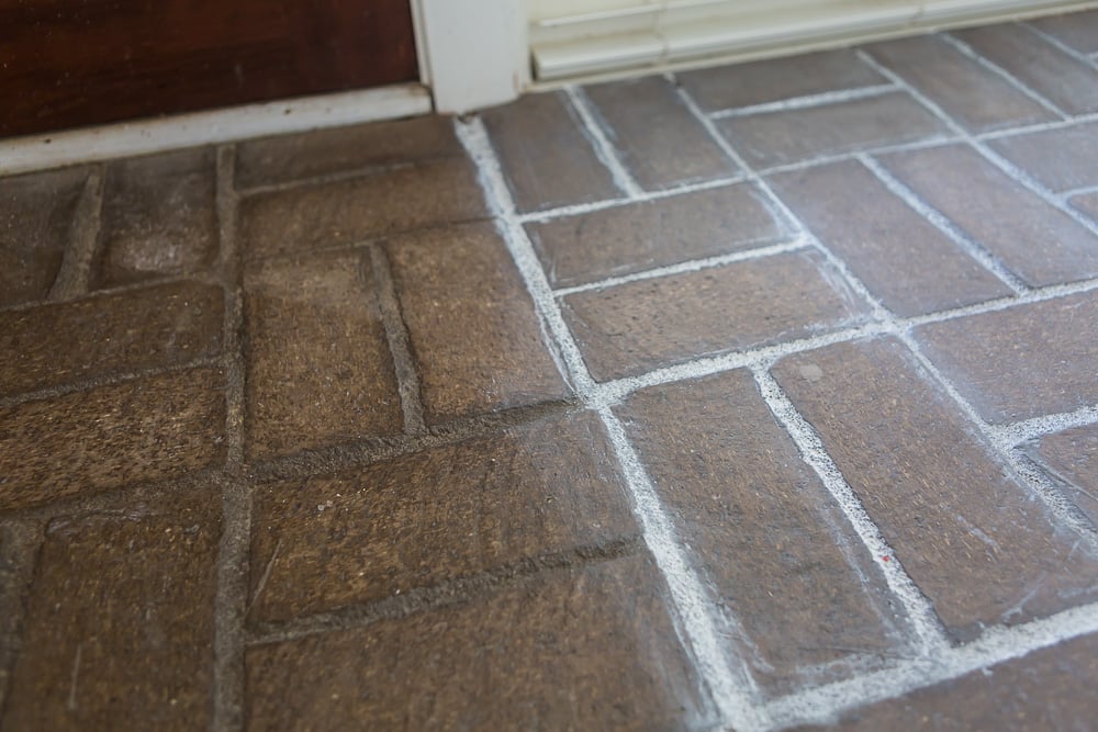 Close-up photo showing the before and after of the brick floor side by side with grout paint and without.