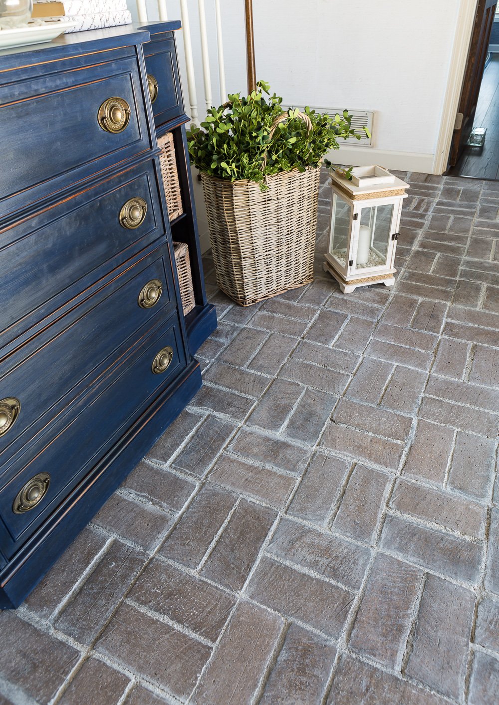 Foyer with blue sideboard and brick floor that was washed over with grout paint. 