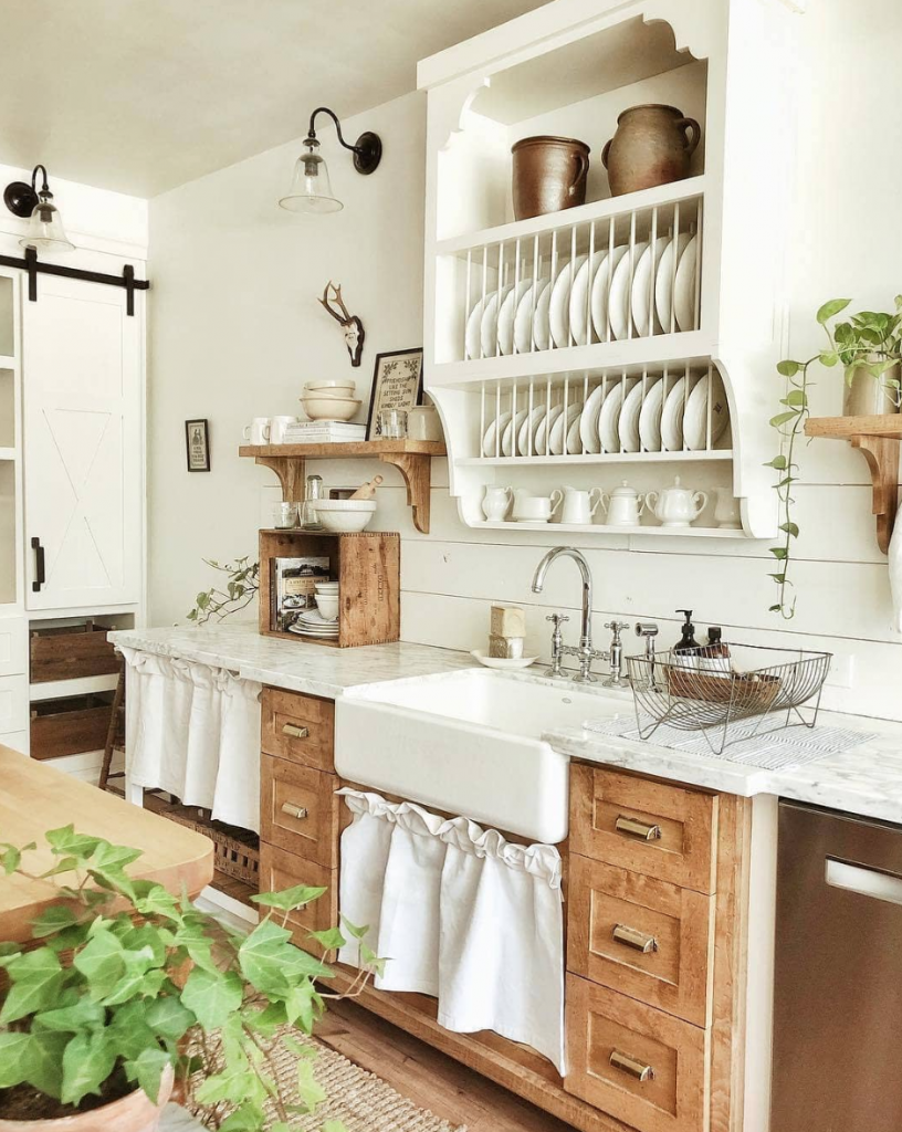 Farmhouse kitchen with skirted table in front of sink. 