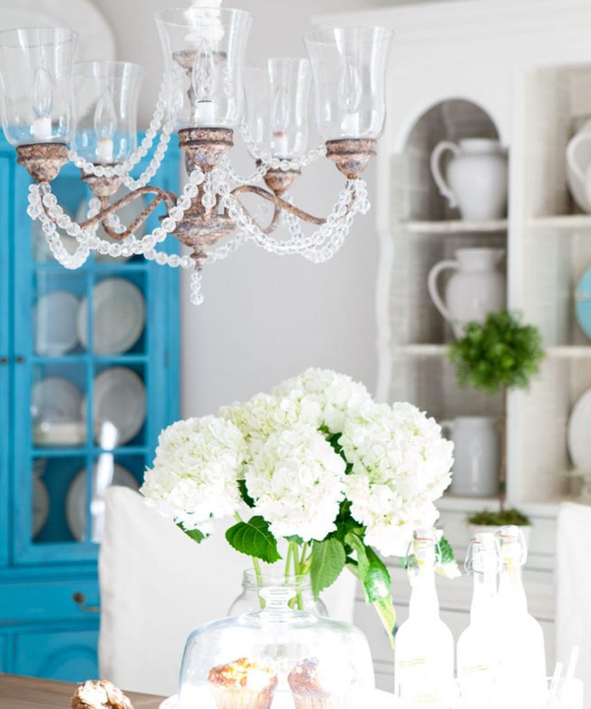 pretty white and turquoise dining room with rustic crystal chandelier.