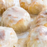 Baked apple dumplings covered with hard sauce on a plate.