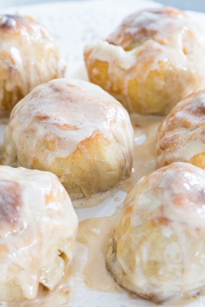 Baked apple dumplings covered with hard sauce on a plate.