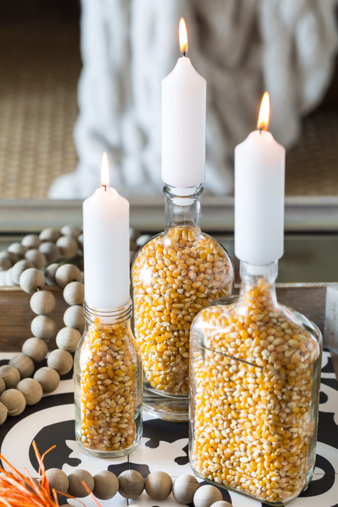 Close up of 3 popcorn filled glass bottle fall candle holders.