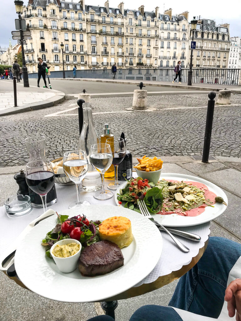 Eating dinner at a small chic round table at an outdoor cafe in Paris.