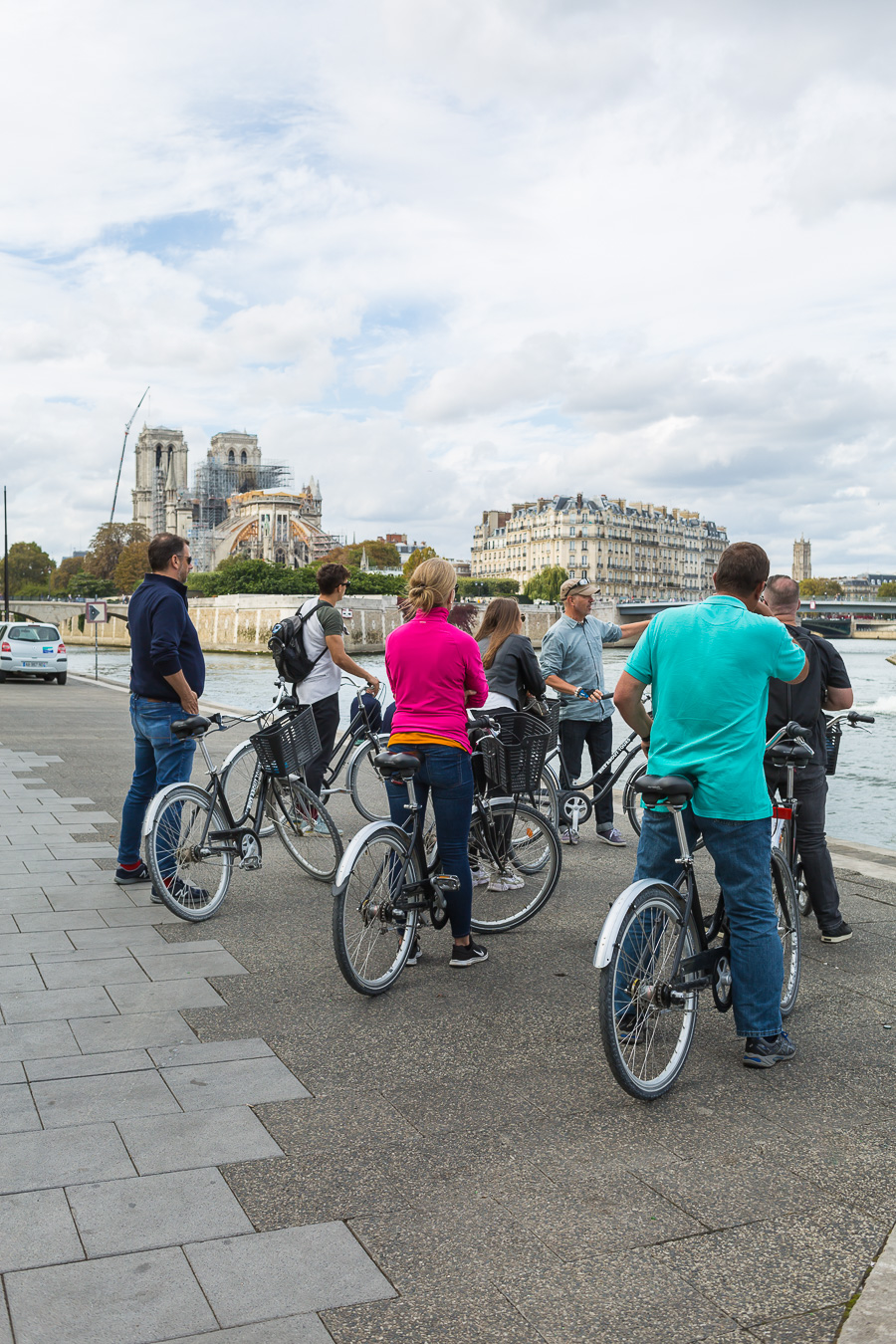 Bicycle riders stopping along the Seine in Paris to listen to a tour guide.