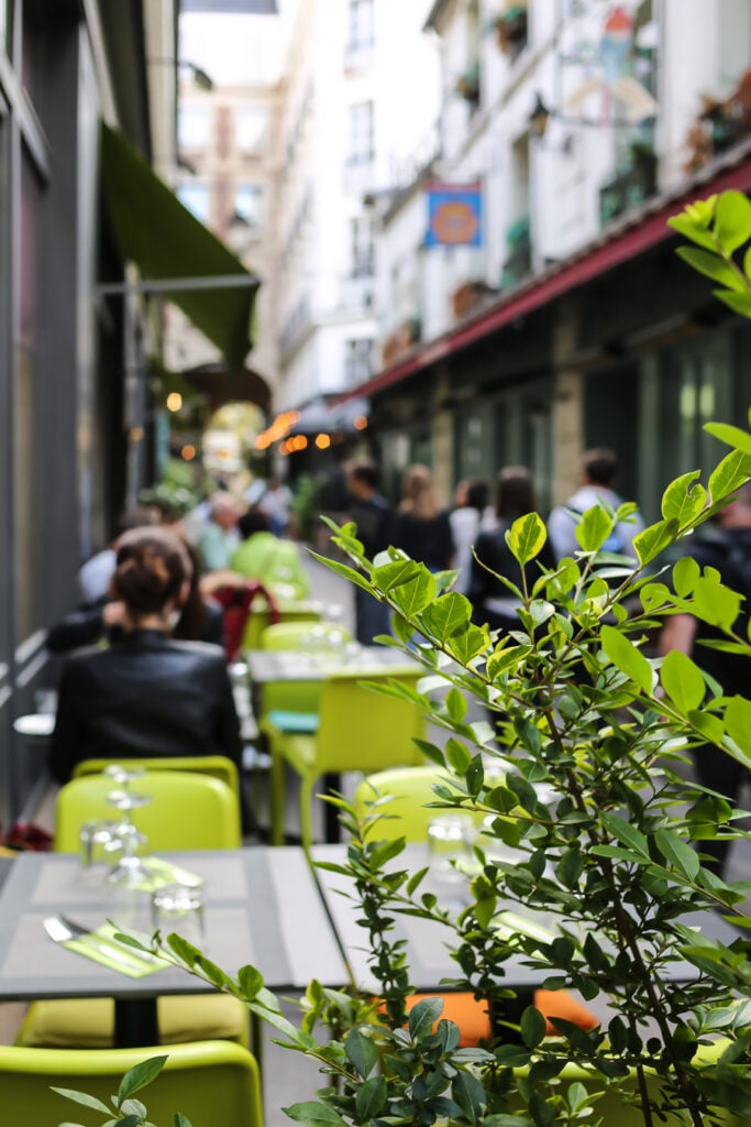 Tiny cobblestone street with cafes and shops in Paris.