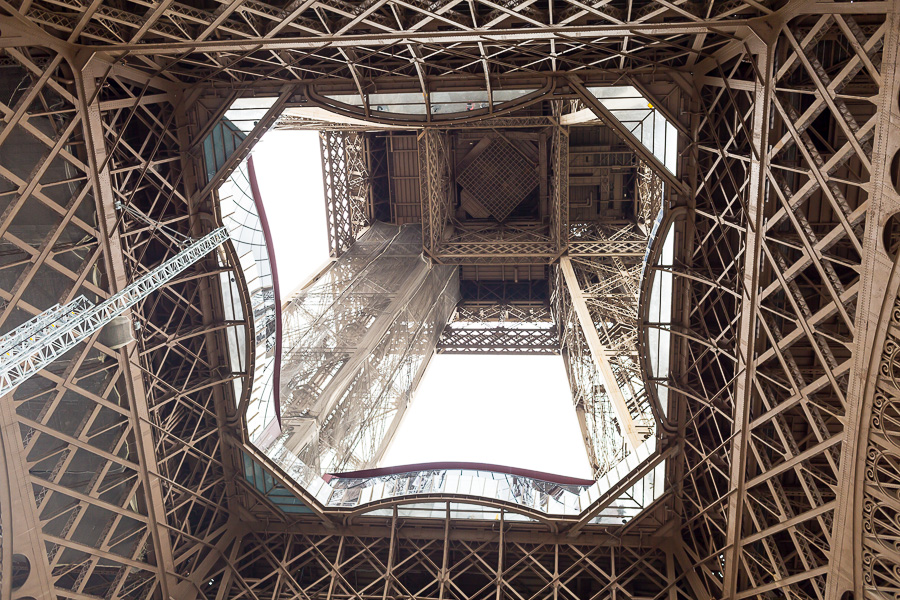 Standing under the Eiffel Tower and looking up inside it.
