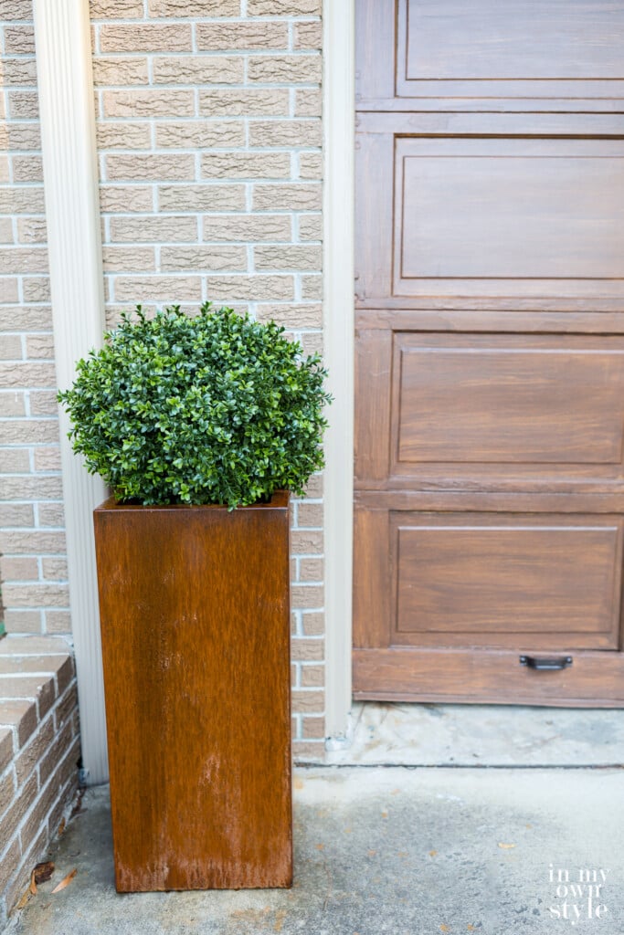 A corten steel tall planter in a driveway