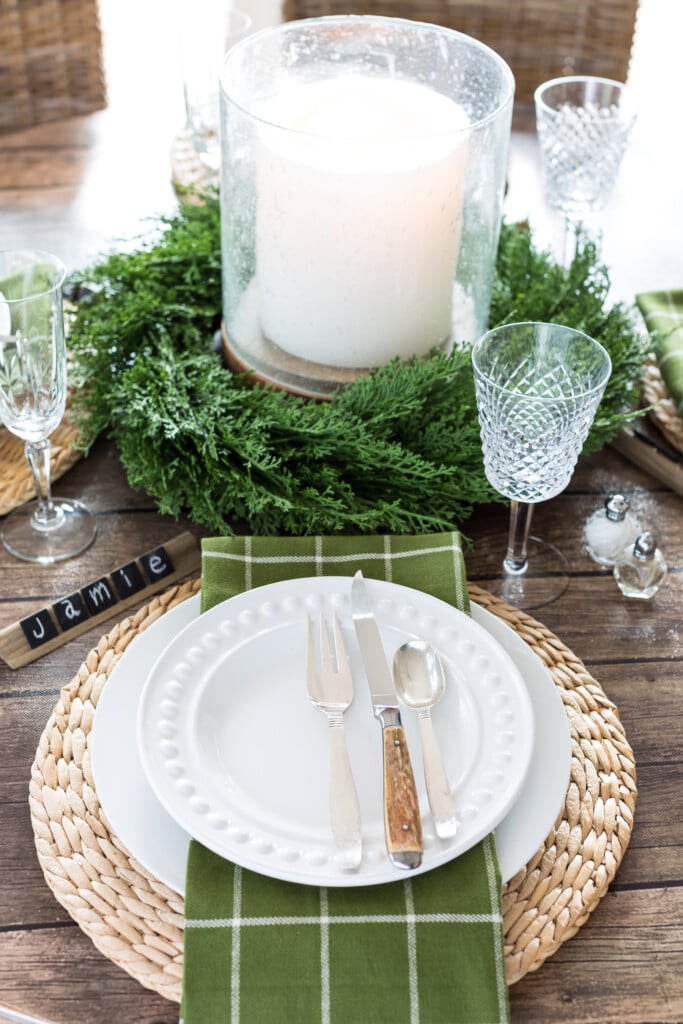 Dark wood look dining table cover with large bubble glass candle in center of table.