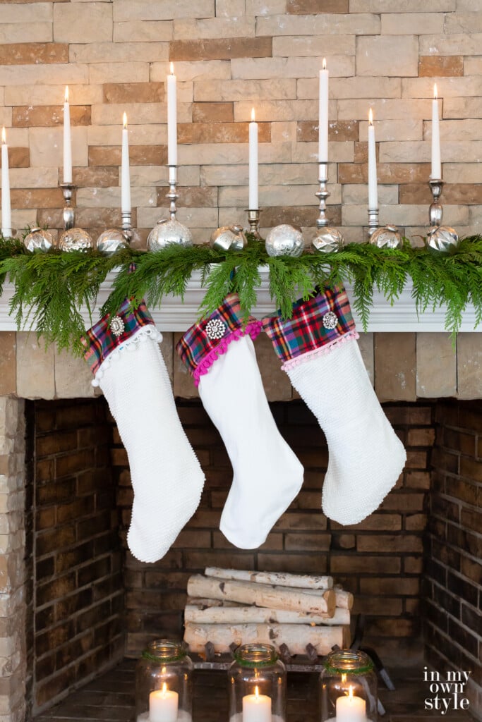 3 White Christmas stockings hung along a white mantel on an AirStone fireplace.