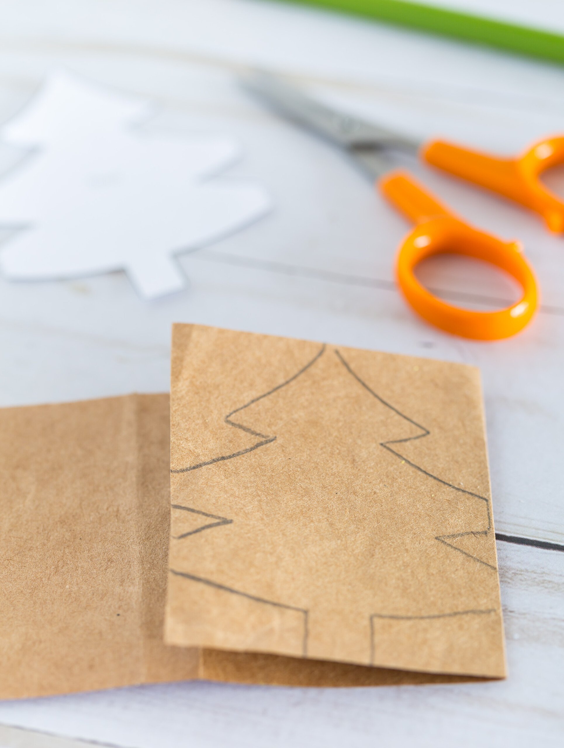 How to start folding a template of a Christmas tree pattern on to a strip of paper.