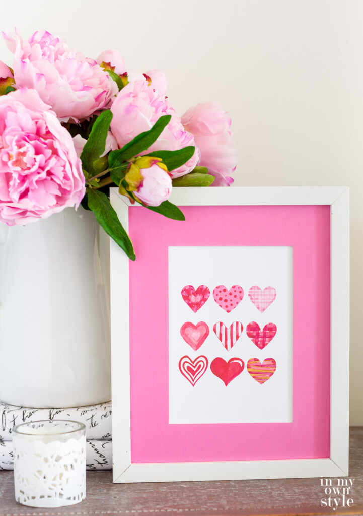 Free printable art of 9 Valentine hearts in a white frame.