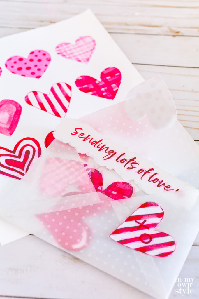 Free printable Valentine envelope filled with pink and red watercolor hearts.