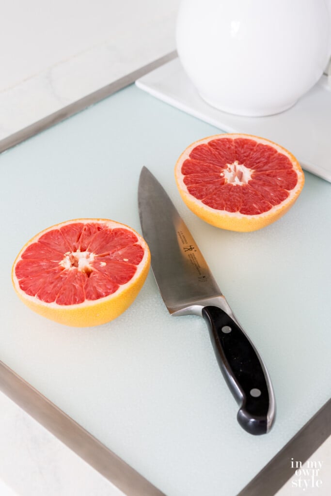 Grapefruit being cut on a tempered glass in-set in counter cutting board.