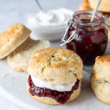 Close up of a vegan scone filled with raspberry jam and cream.