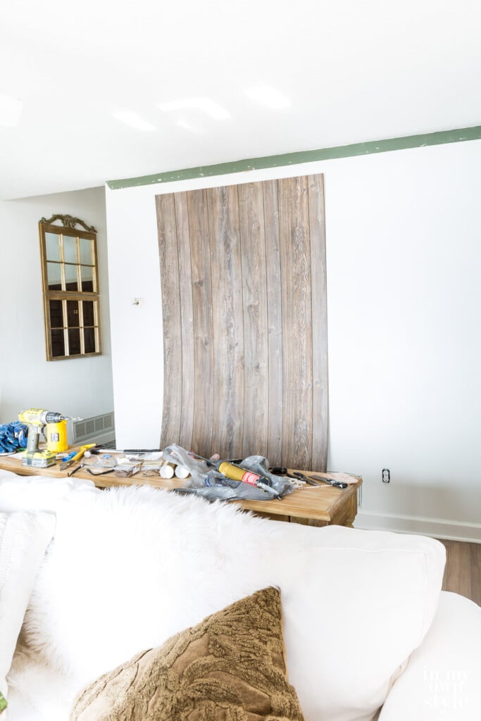 Installing barnwood sheet paneling to a living room.