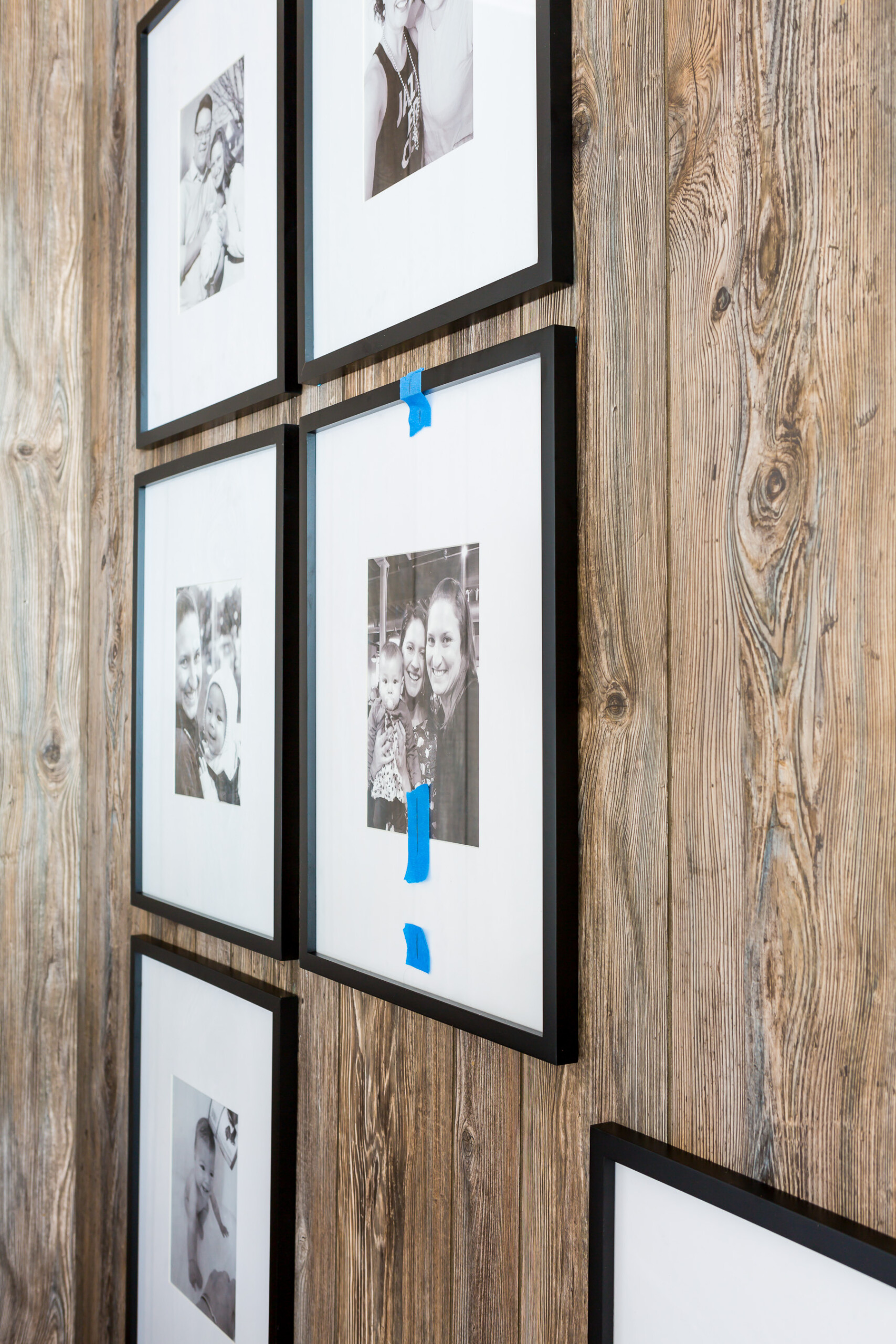 Hanging frames in a grid style on a paneled wall.