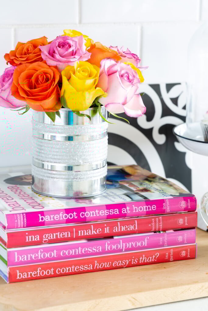 Tin can vase on a stack of books on a kitchen counter.