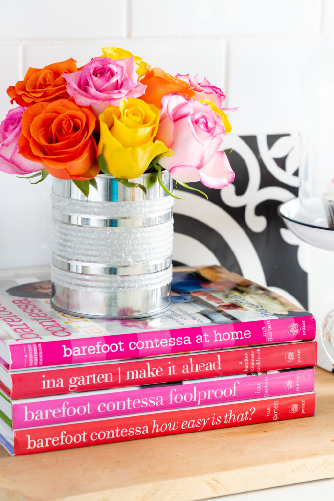 Tin can vase on a stack of books on a kitchen counter.
