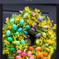 Colorful plastic Easter Egg wreath on black door.