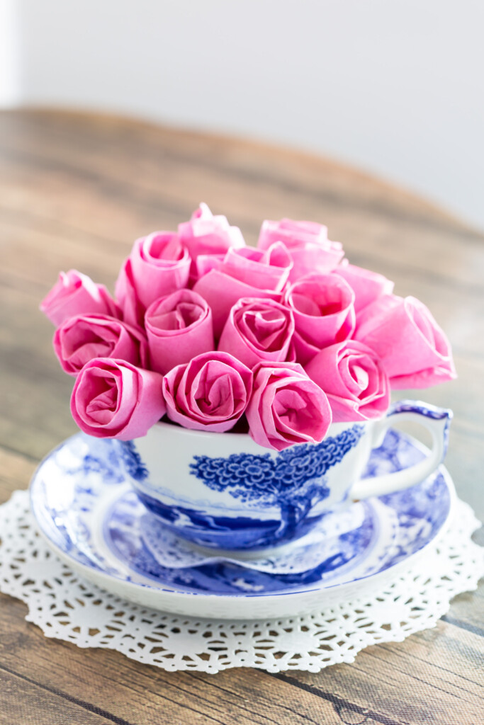 Pink paper roses in a blue and white teacup vase.
