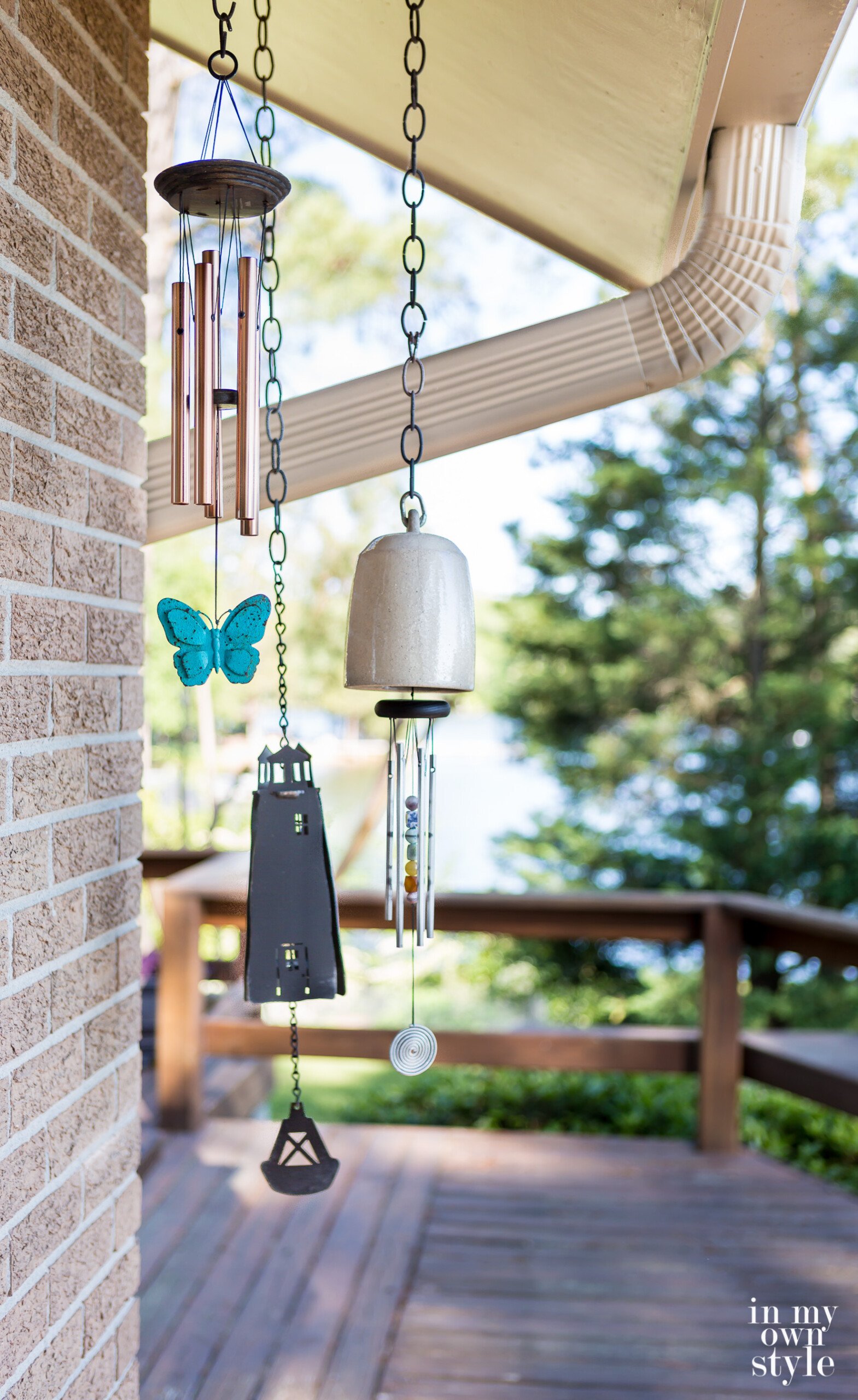 A collection of wind chimes hanging from a house. Each chime has a different look and sound. 