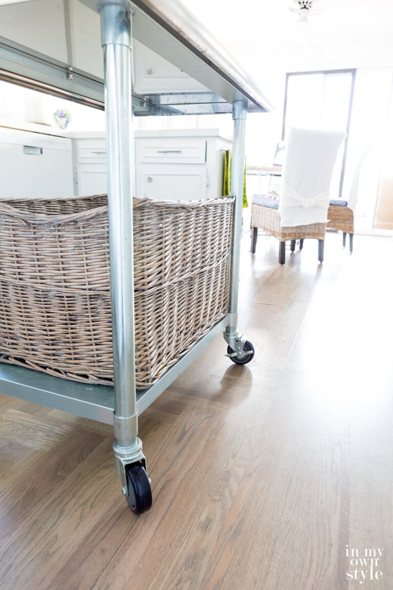 Movable metal rolling island in a small white kitchen.