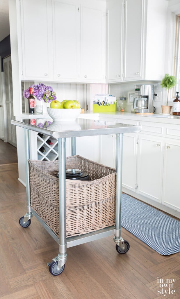 Movable metal rolling island in a small white kitchen.