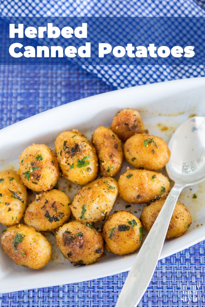 Seasoned and herbed encrusted canned potatoes in a white serving dishes being spooned out.