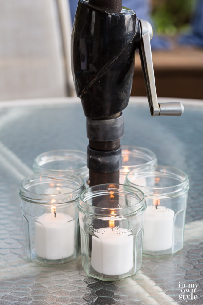 5 jelly jars turned into pretty votive candle holders around a patio tables umbrella pole.