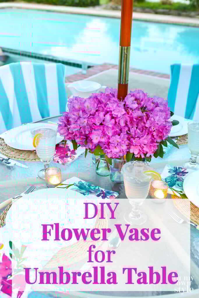 Pink flowers on a patio table with an umbrella pole in the center. Copy says DIY Flower Vase for Umbrella Table.