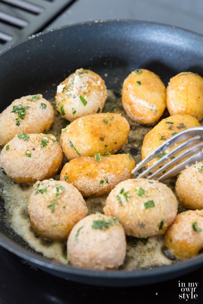 Frying canned potatoes in butter on a stovetop.