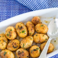 Herbed canned potato recipe served in white dish on blue table cloth.