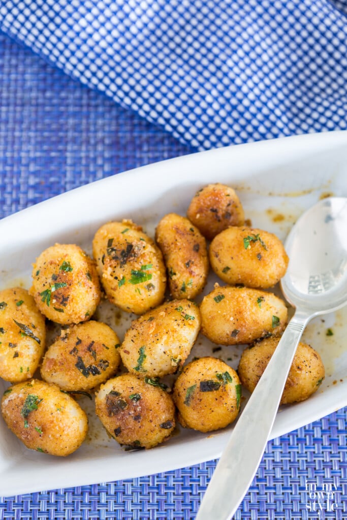 Herbed canned potatoes served in white dish on blue table cloth.