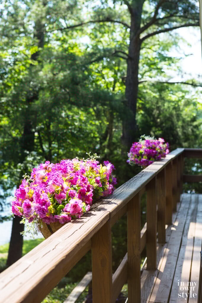 Window box flower planters with fake flowers on deck railing.