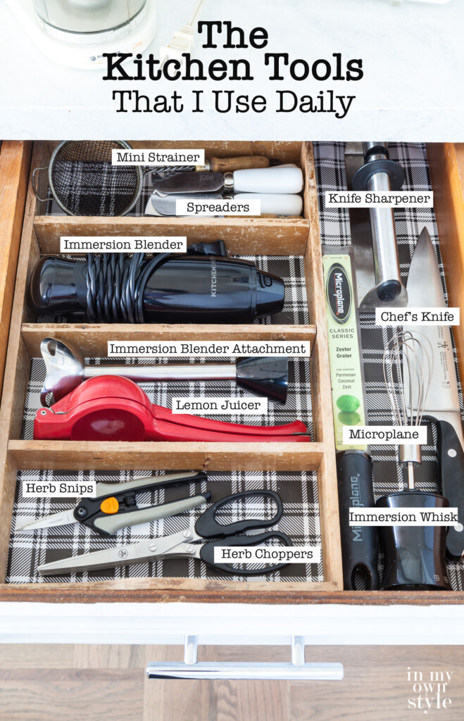 Open kitchen drawer showing all the tools inside. Text overlay says what each item is - Mini Strainer Spreaders, Knife Sharpener, Immersion Blender, Chef's Knife, Microplane, Herb Snips
